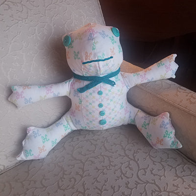 Plush toy coqui frog made with pastel colored coquies in a criss cross pattern
